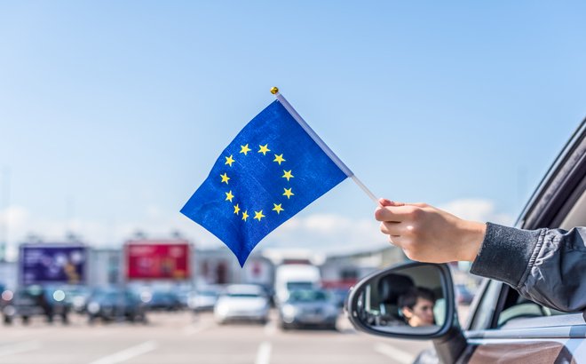 Boy,Holding,Europe,Or,European(eu),Flag,From,The,Open,Car